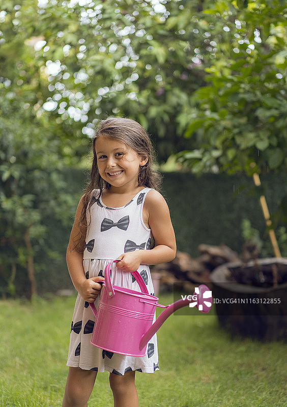 在后院拿着喷壶的可爱小女孩图片素材