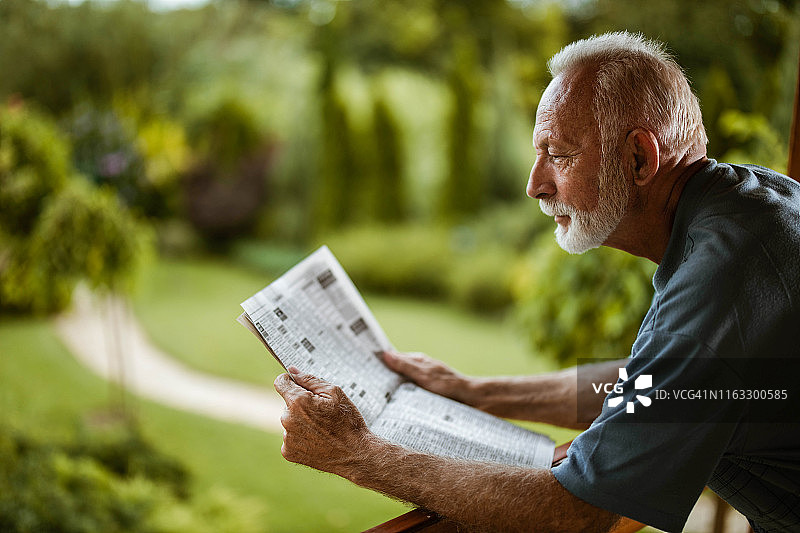 中年男人在露台读报的侧面图片素材
