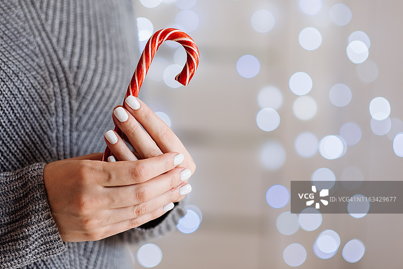 女孩手捧可可饮料，配有奶油和薄荷糖。圣诞节假日概念。节日背景。冬季背景。节日庆祝散景图片素材