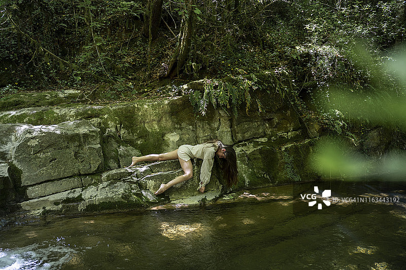 年轻女人躺在西班牙加罗特沙的天然水池边图片素材