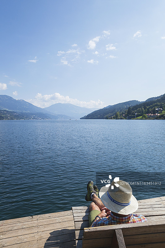 男人在湖岸边休息，位于奥地利克恩顿州米尔施塔特湖畔的塞博登图片素材
