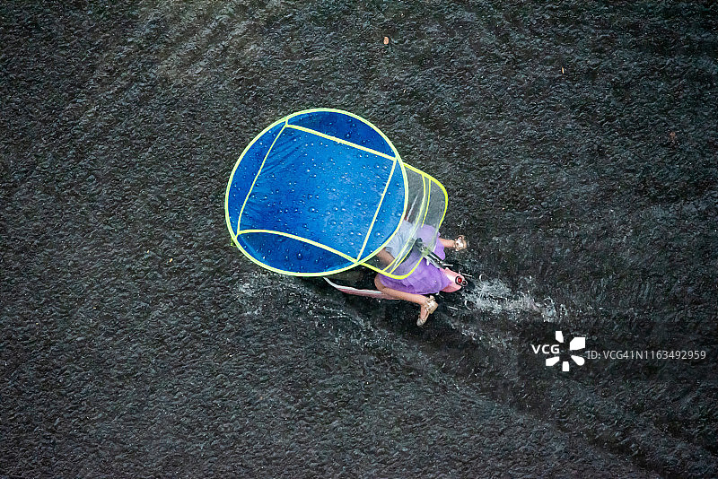 雨中撑伞的滑板车图片素材