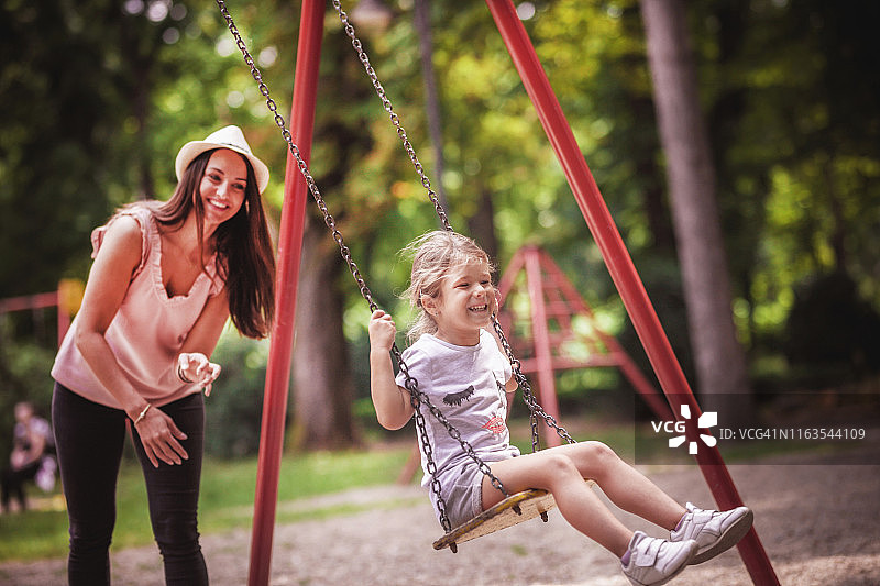 快乐的母亲在公园荡秋千图片素材