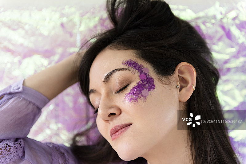 脸颊上涂着紫色闪粉的女人图片素材