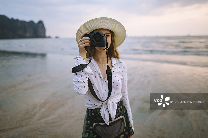 年轻女人在泰国甲米的海滩上拍照图片素材