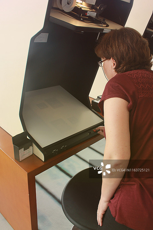 准备缩微胶片阅读器的老年女图书管理员图片素材