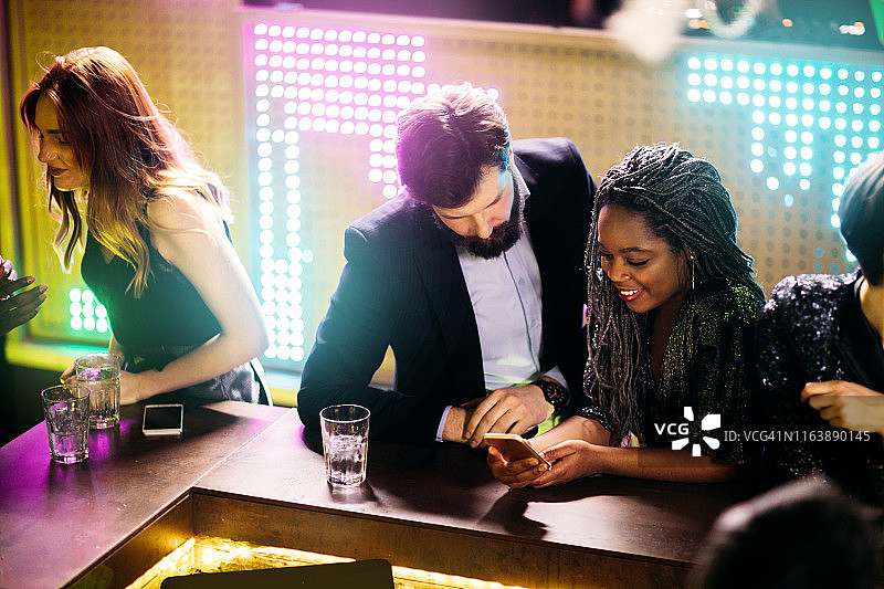 朋友们在夜总会使用智能手机图片素材