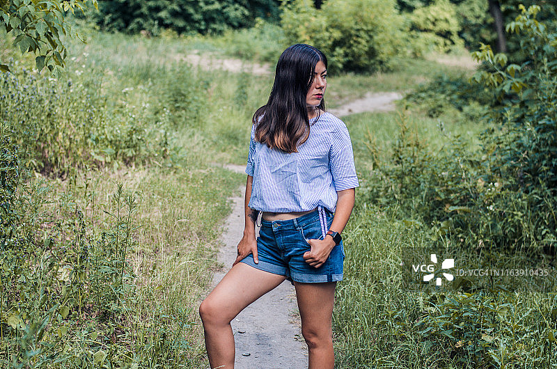 身穿白色衬衫和蓝色牛仔短裤的年轻白人女性的肖像图片素材