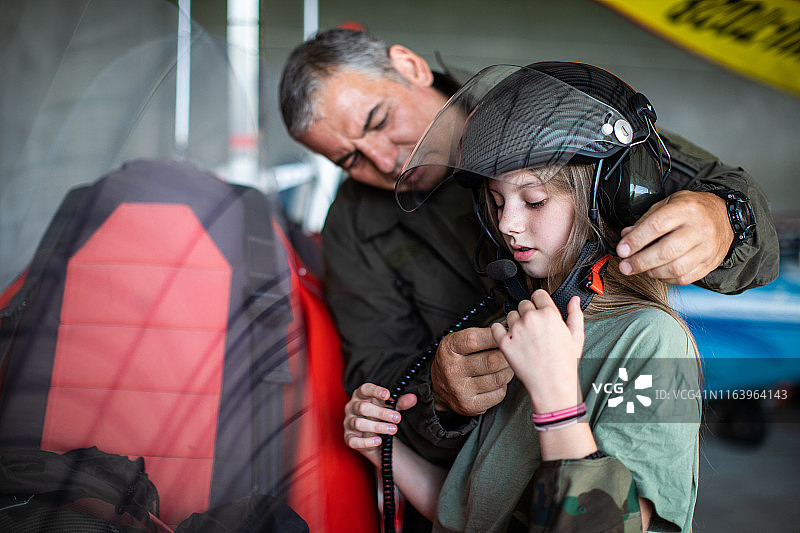 飞行教员在机库里帮助戴头盔的女孩图片素材