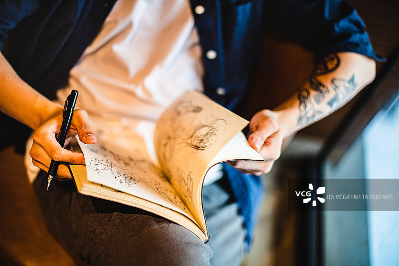 亚洲青年男子坐着在笔记本上素描图片素材