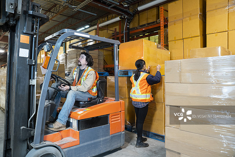 工业仓库工作场所安全主题：叉车后方危险区域作业的工人图片素材