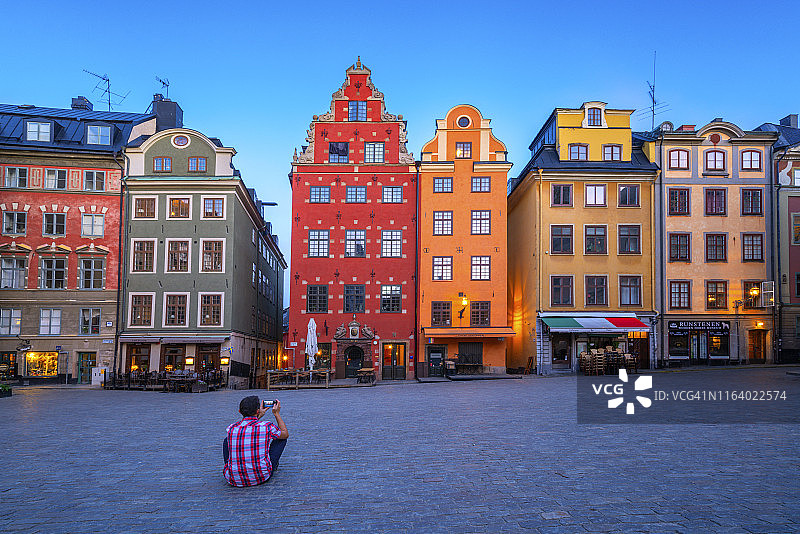 男子在斯德哥尔摩老城用智能手机拍照图片素材