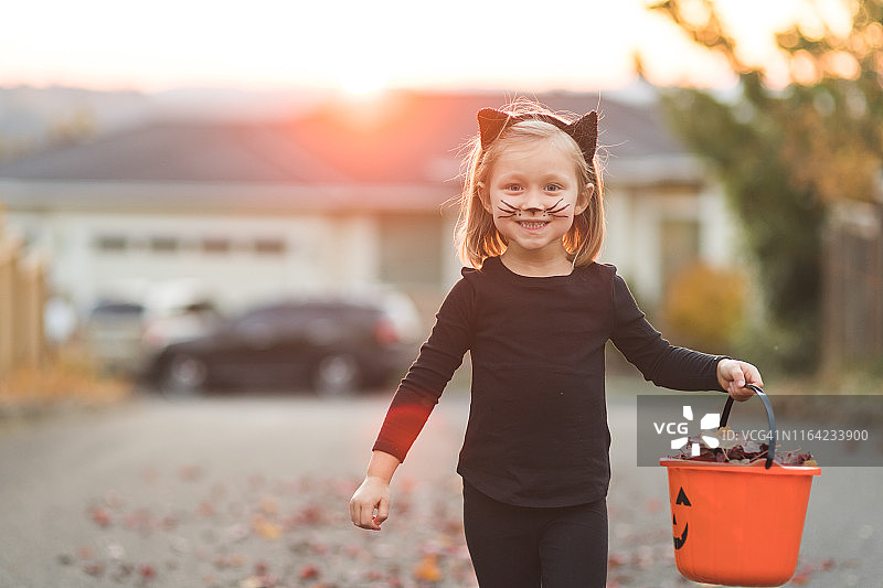 身穿黑色猫咪服装的年轻女孩在不给糖就捣蛋图片素材