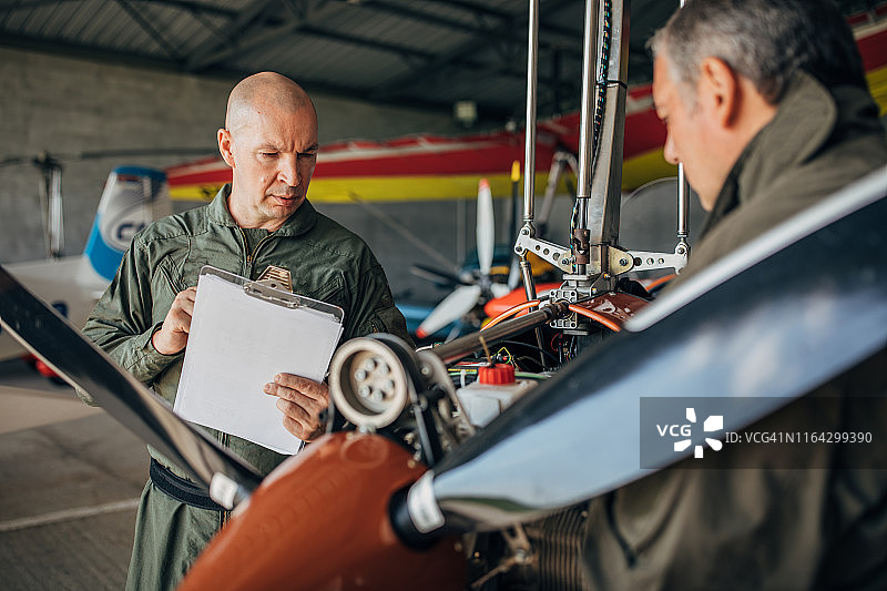 正在修理螺旋桨飞机引擎的两名技工图片素材