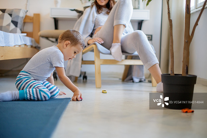 幼儿穿着睡衣在地板上玩玩具车图片素材