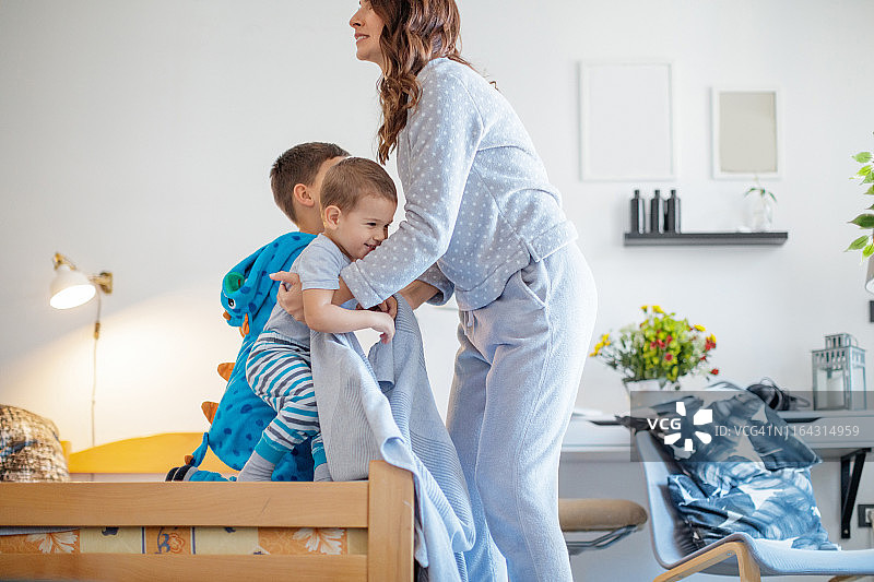 母亲拥抱站在床边的儿子们图片素材