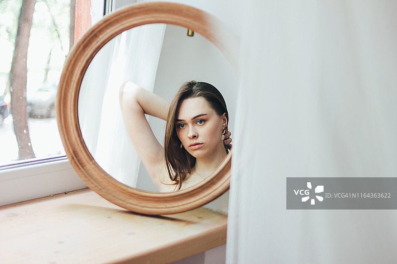 圆形镜子前，柔光下的时尚长发女孩图片素材