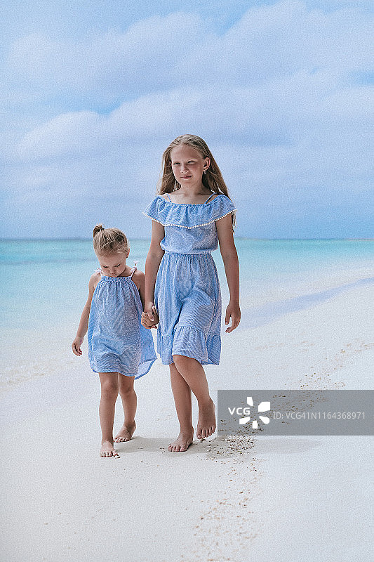 穿着相配服装的两姐妹一起散步，大女儿和小女儿，姐妹俩在度假图片素材