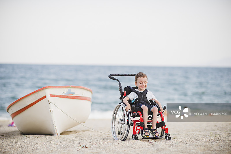 坐在轮椅上的可爱小男孩在海边图片素材