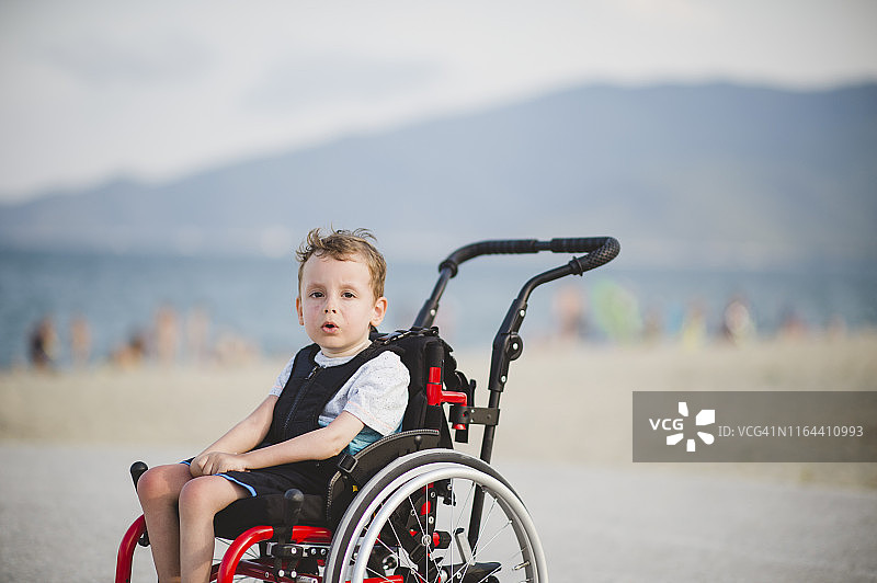 坐在轮椅上的可爱小男孩在海边图片素材