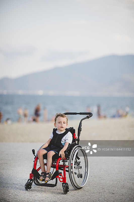坐在轮椅上，在海边微笑的男孩图片素材
