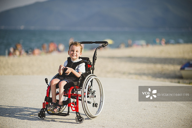 坐在轮椅上，在海边微笑的男孩图片素材