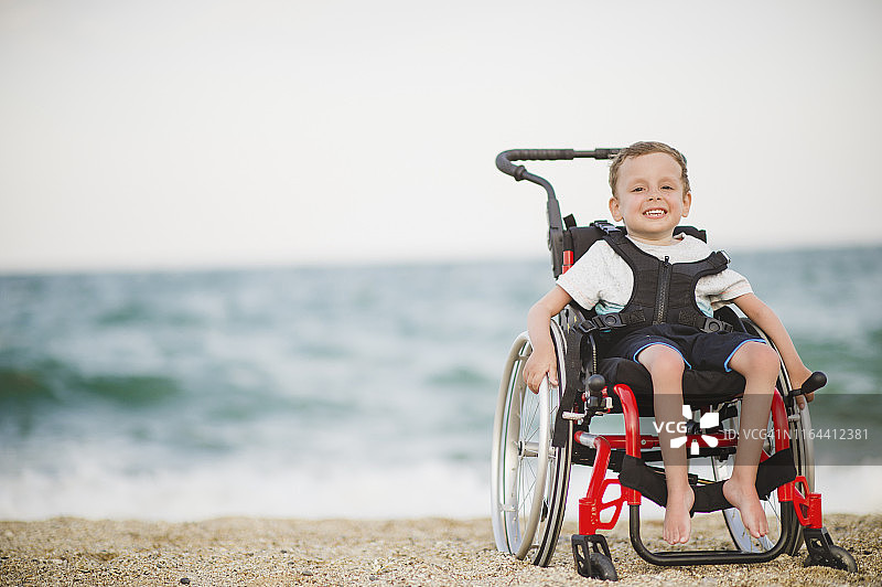 坐在轮椅上，在海边微笑的男孩图片素材