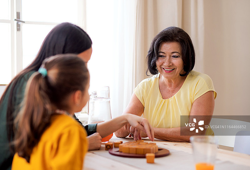 祖母、母亲和孙女坐在家里的桌旁玩棋盘游戏图片素材