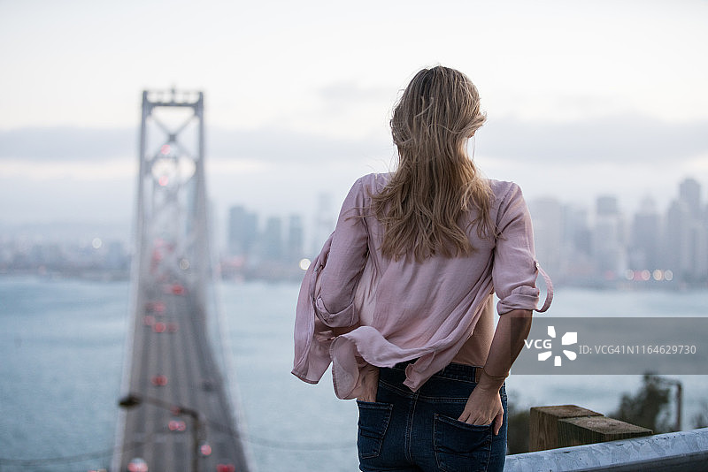 女人眺望旧金山天际线和海湾大桥图片素材