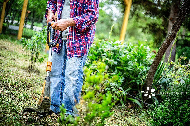 老人正在院子里割草图片素材