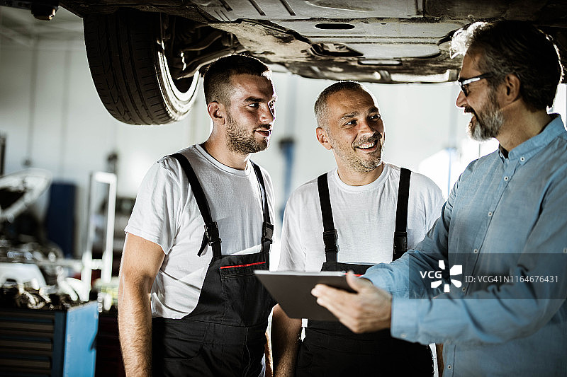 汽车修理工和经理在车间使用数位板交谈图片素材