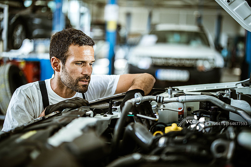年轻汽修工检查车间里的发动机问题图片素材