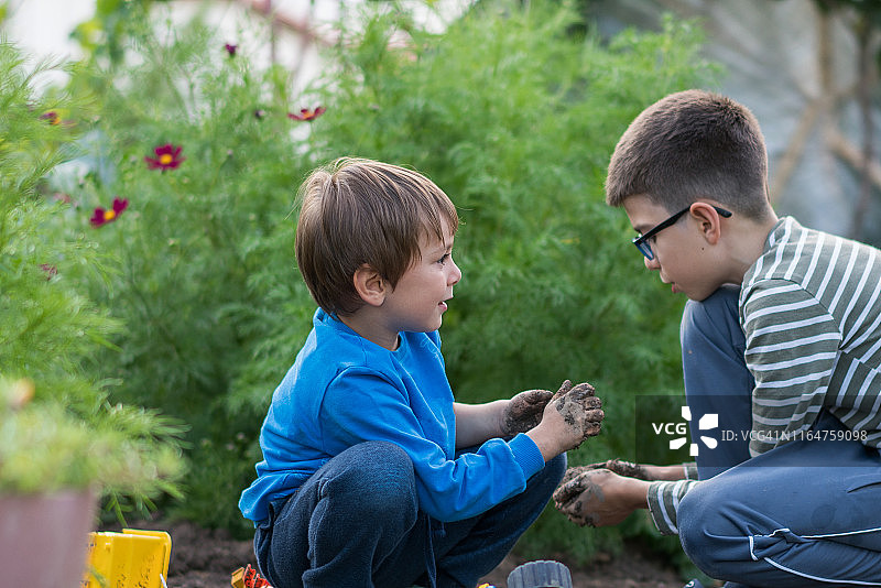 小兄弟在泥地里玩玩具卡车图片素材