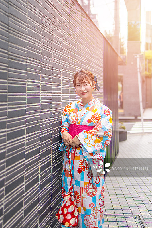 身穿浴衣的年轻女子站在城市街道上图片素材