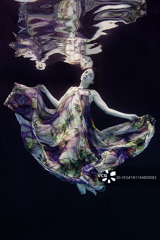 水中流动连衣裙的迷人女性与倒影图片素材