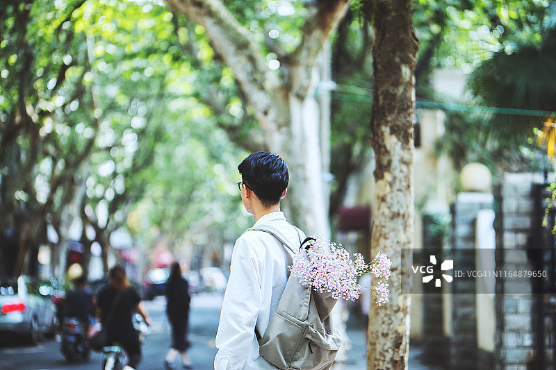 背着装满鲜花背包走在街上的男人图片素材