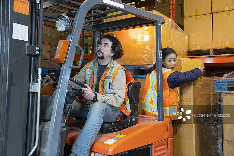 工业仓库工作场所安全主题：叉车后方危险区域作业的工人图片素材