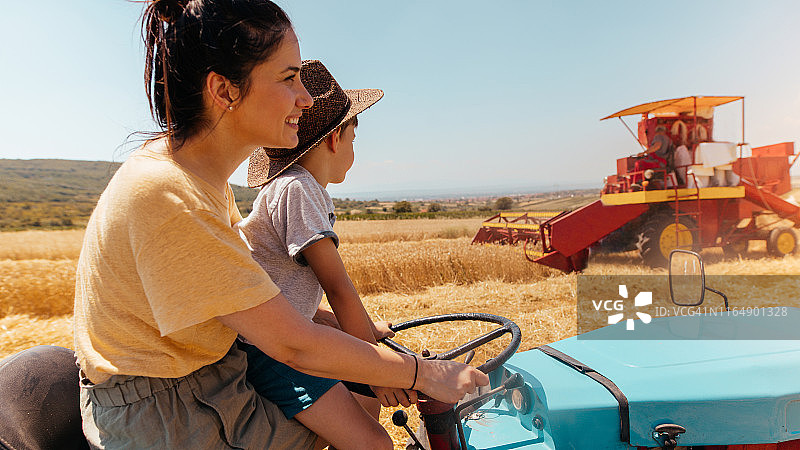 收获期间母亲和儿子在拖拉机上图片素材