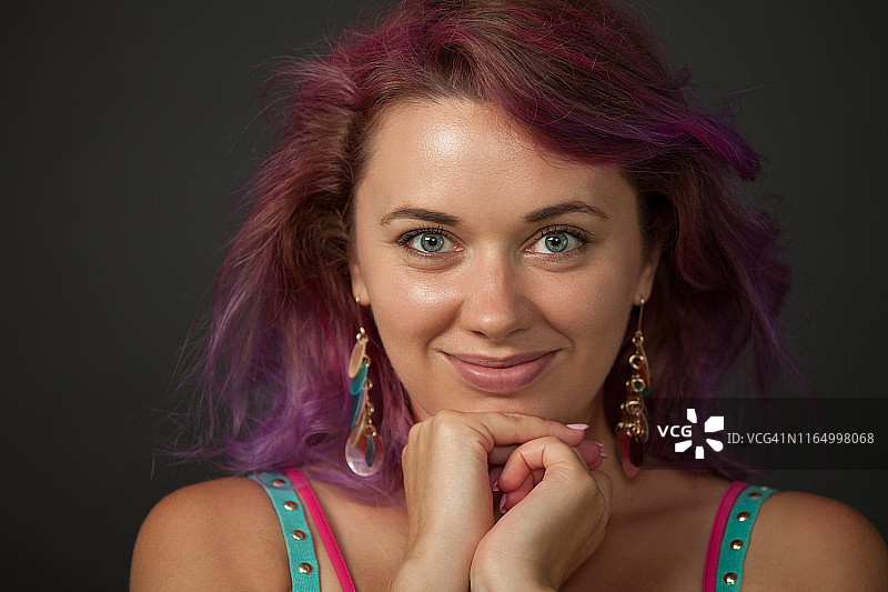30岁紫发女子在黑色背景下的工作室肖像图片素材