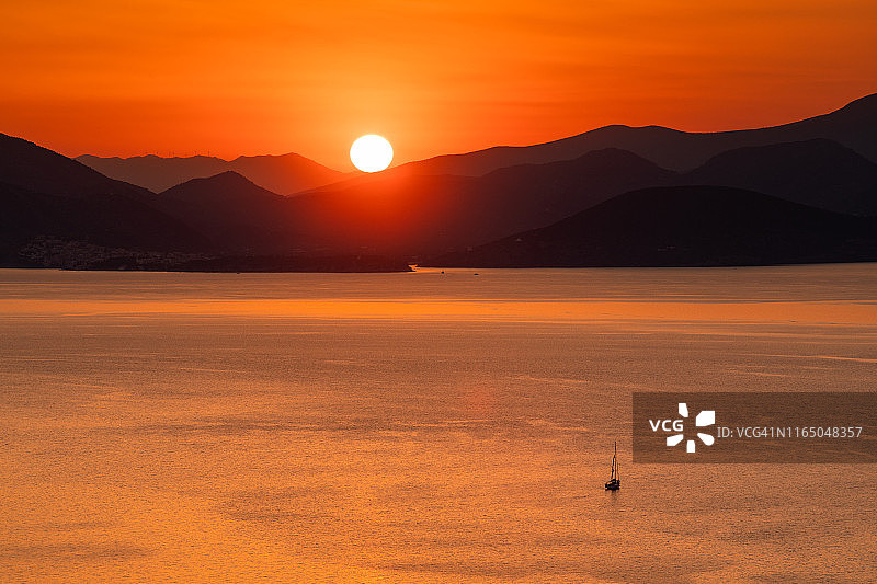 日落时分在寂静的海面上航行的孤独游艇图片素材