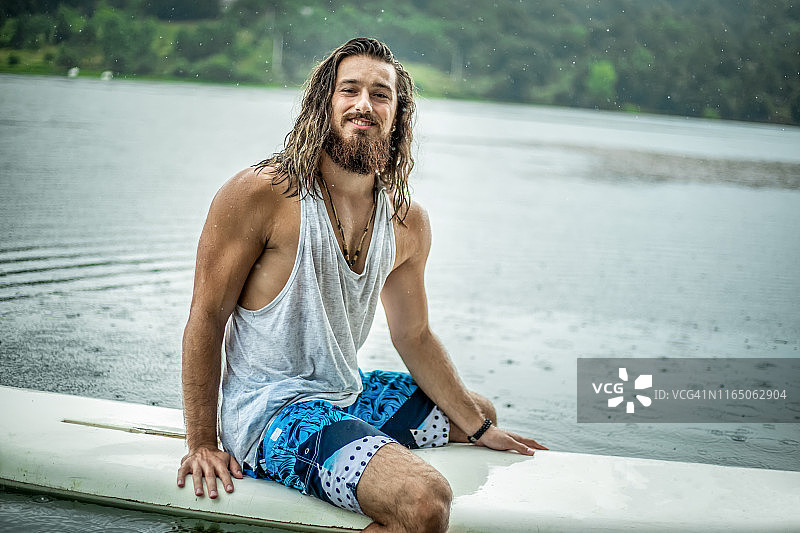 帅气的冲浪者在大海中手持冲浪板图片素材