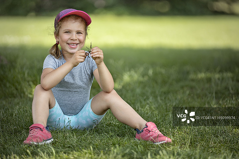 坐在草地上的笑容甜美的可爱小女孩图片素材