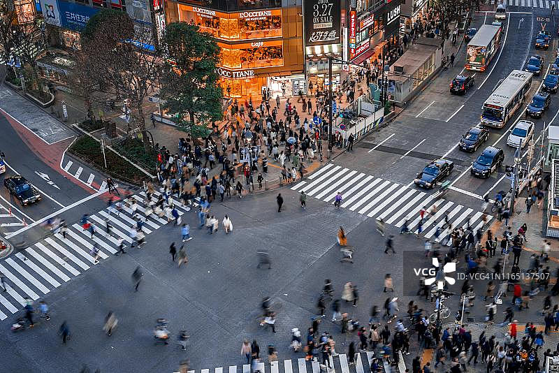 从上方看涩谷十字路口，人群在灯光和彩色标志照亮的十字路口，夜晚的广告牌，涩谷站，日本东京图片素材