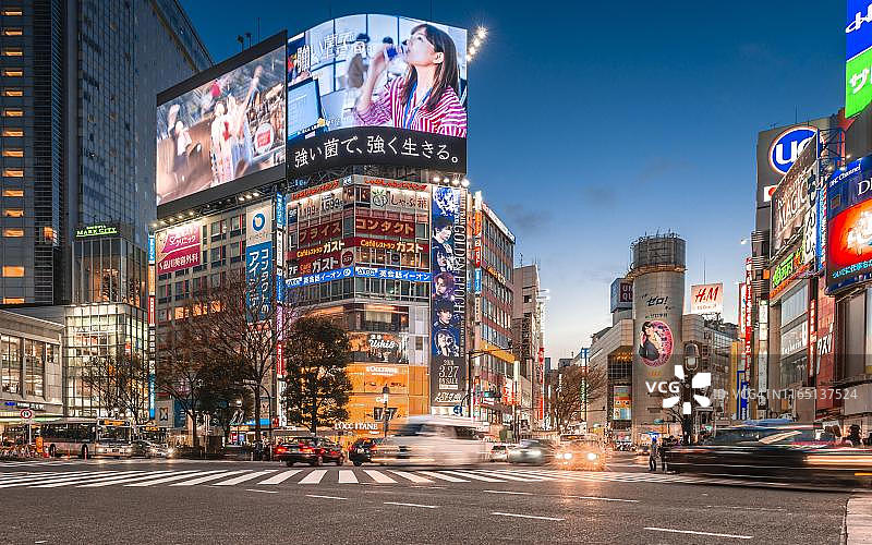 日本东京涩谷十字路口，傍晚时分的车流、彩色和霓虹灯标志图片素材