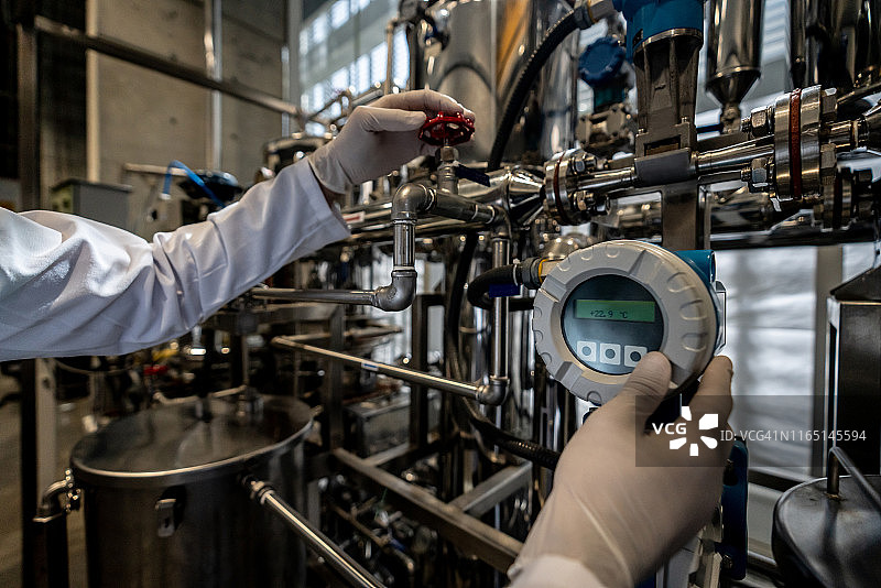 身份不明的人在工艺实验室工作，打开阀门并看着屏幕图片素材