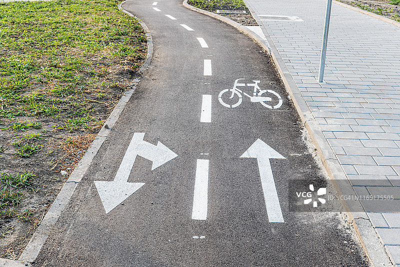 黑色沥青路上带白色自行车标志和方向箭头的自行车道图片素材