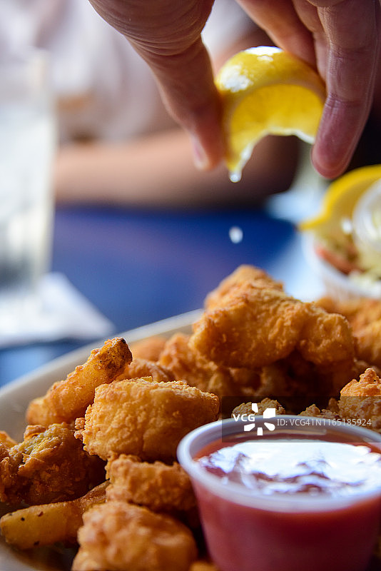 在炸海鲜拼盘上挤柠檬汁图片素材