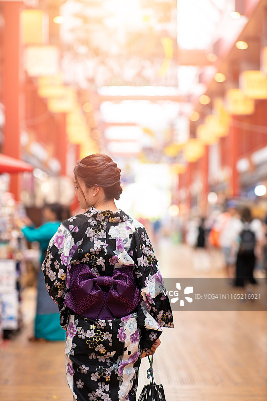年轻女子身穿浴衣走在日本传统商业街的背影图片素材
