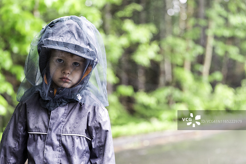 戴着蚊帐帽在露营地玩耍的红发小男孩图片素材
