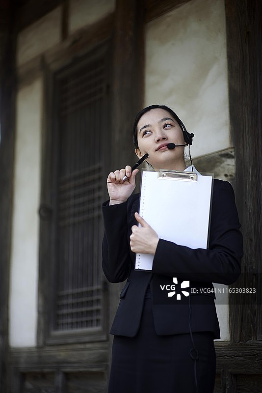 戴耳机拿着写字板的女商人图片素材